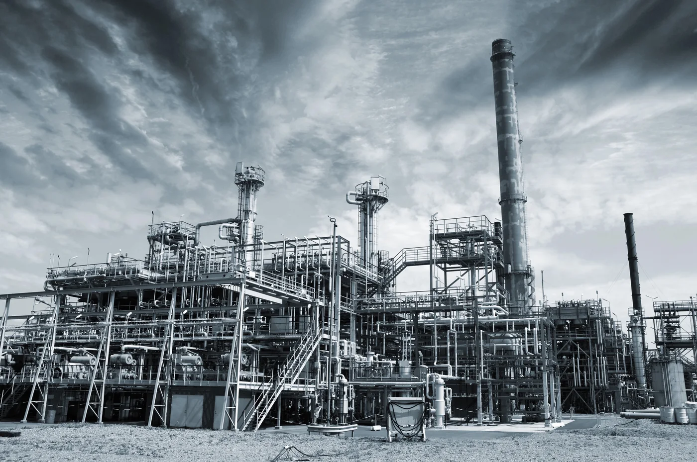 Industrial plant with pipes, towers and a tall smokestack under a stormy sky